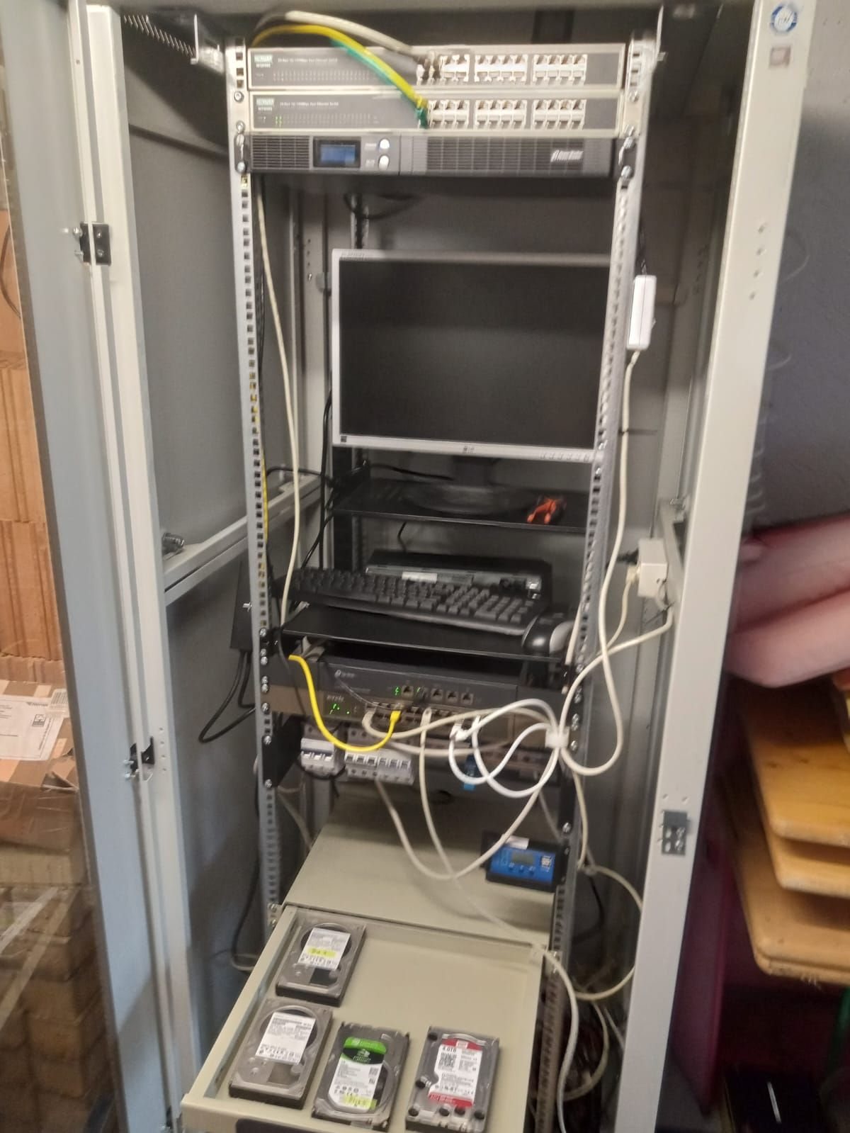 OnTUBS-Serverschrank Anfang 2025 mit Netzwerkkomponenten, Bildschirm und Serverhardware
